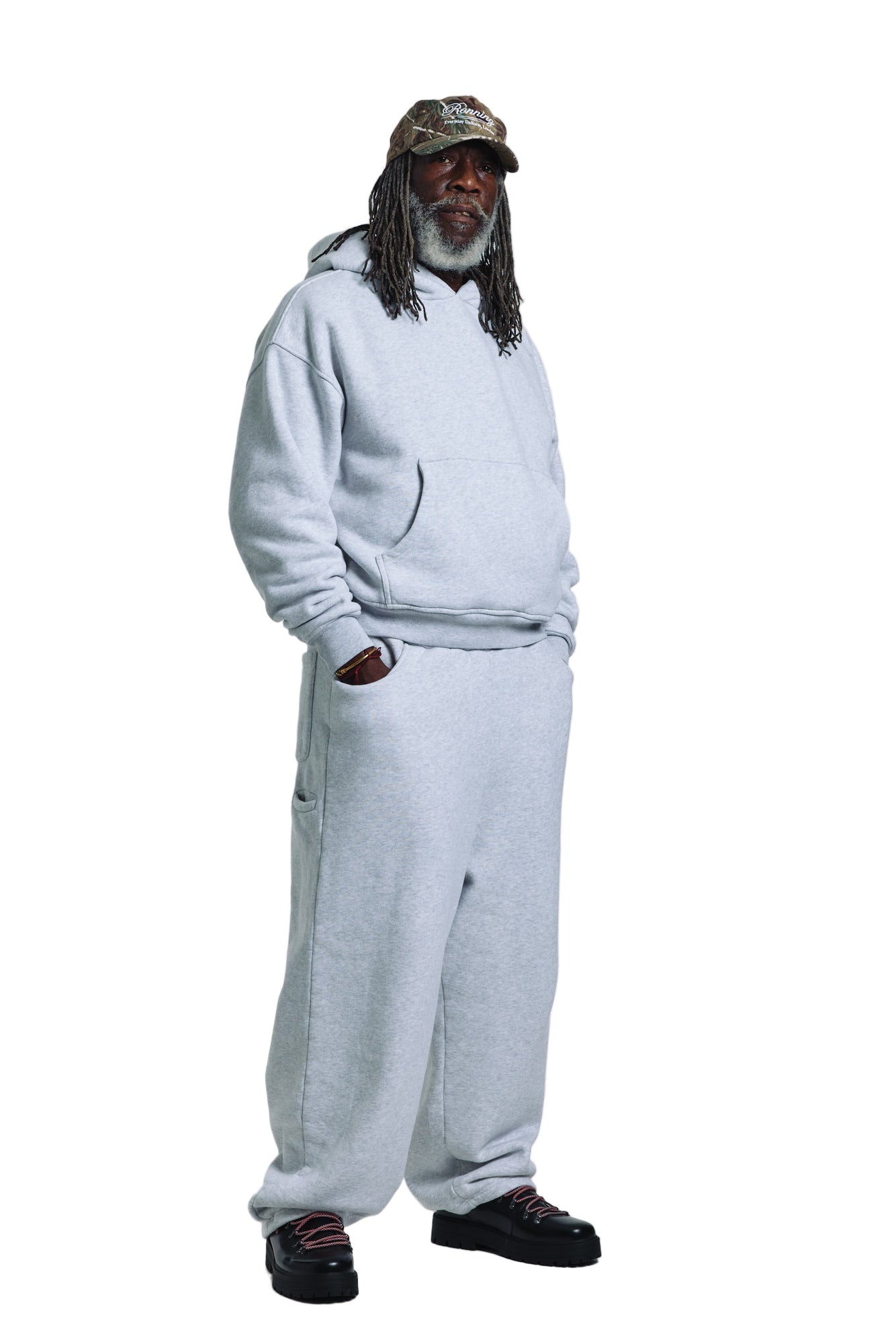 Person wearing a gray tracksuit and cap on a white background