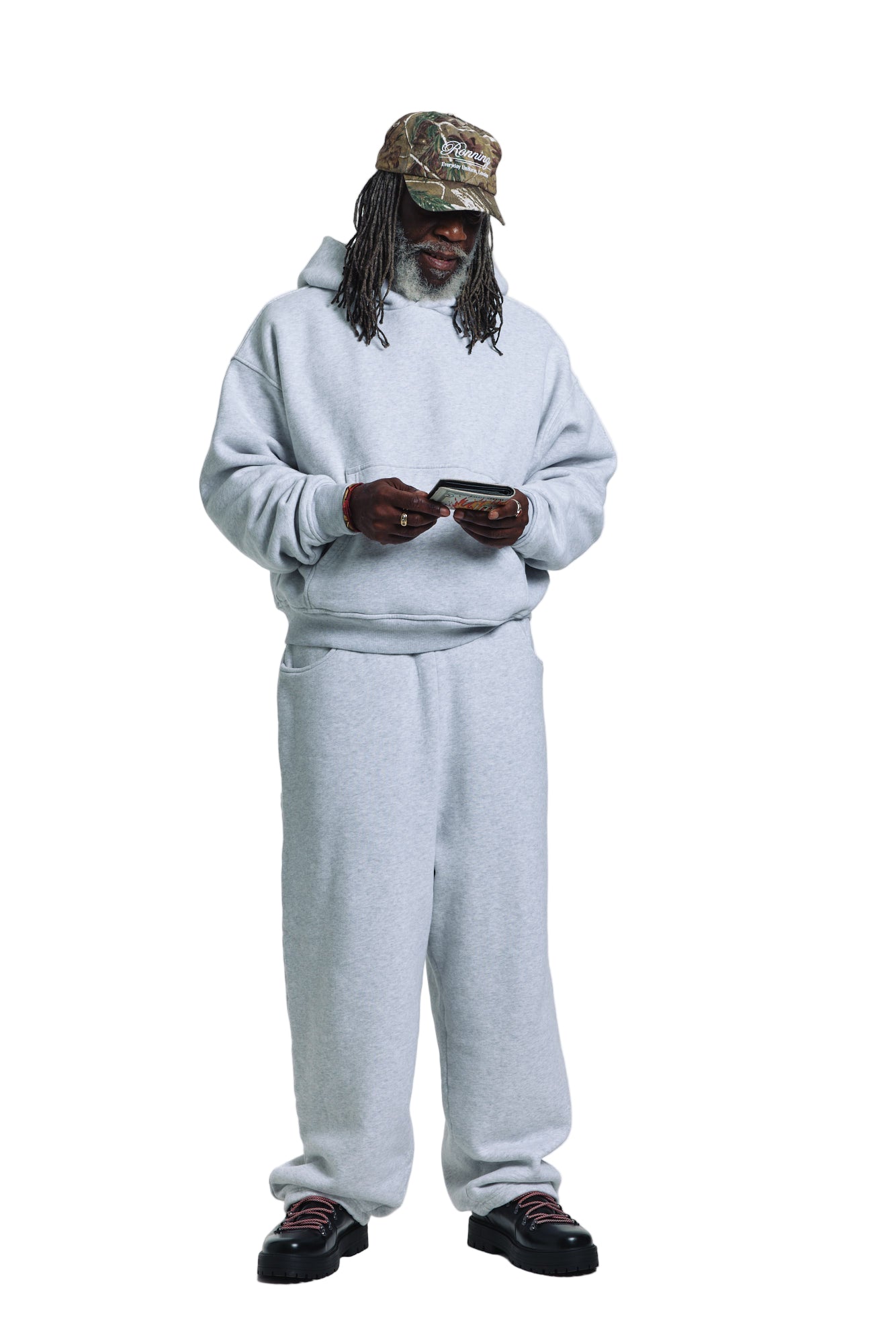 Person wearing a gray tracksuit and camouflage hat on a white background