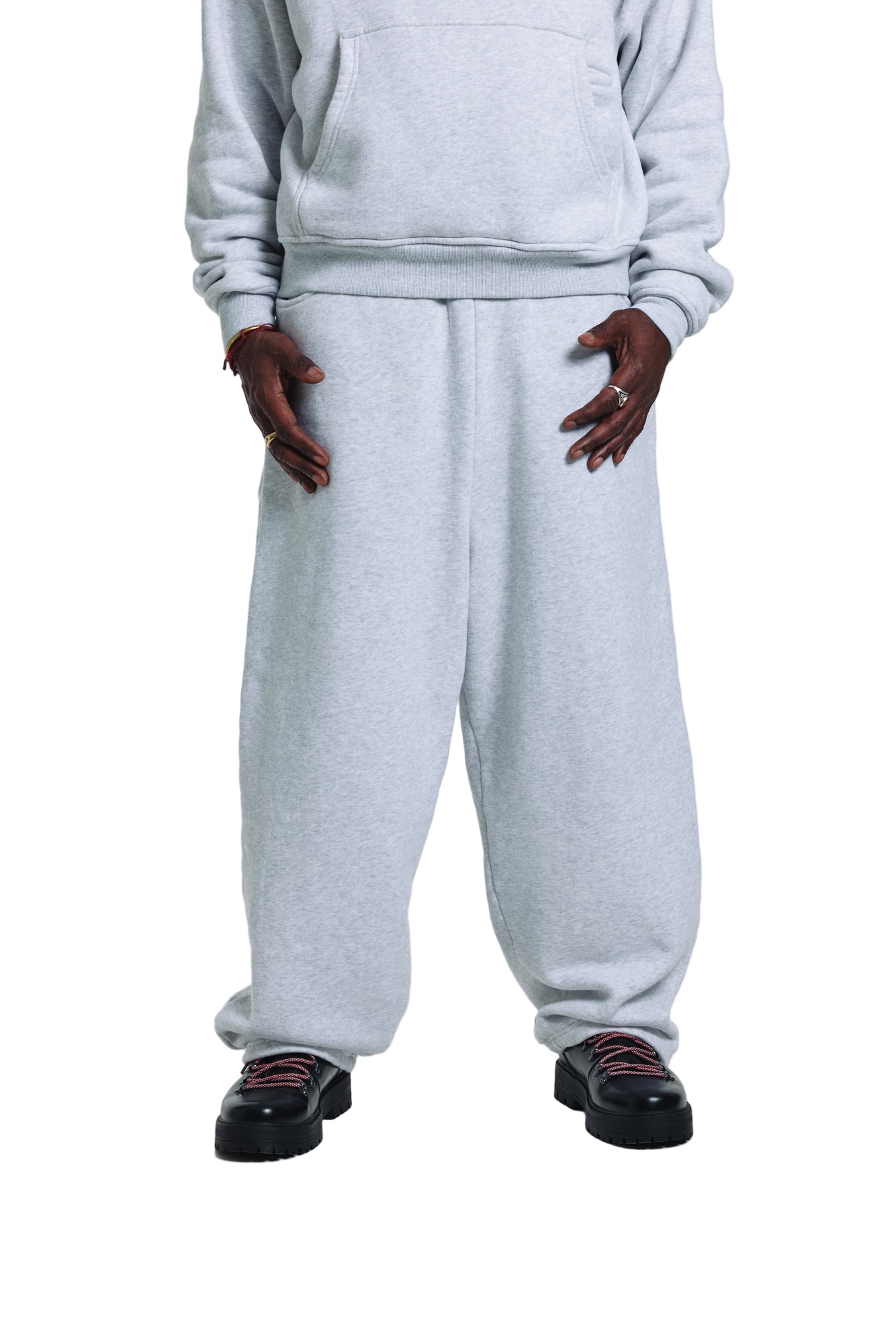 Person wearing a gray sweatshirt and sweatpants with black shoes on a white background